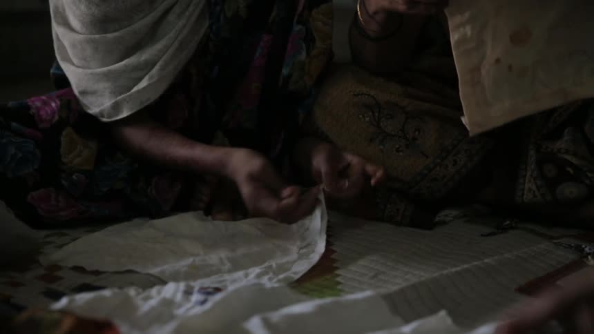 A woman tends to her white cloth through knitting
