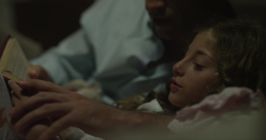 A man reads a book with his daughter
