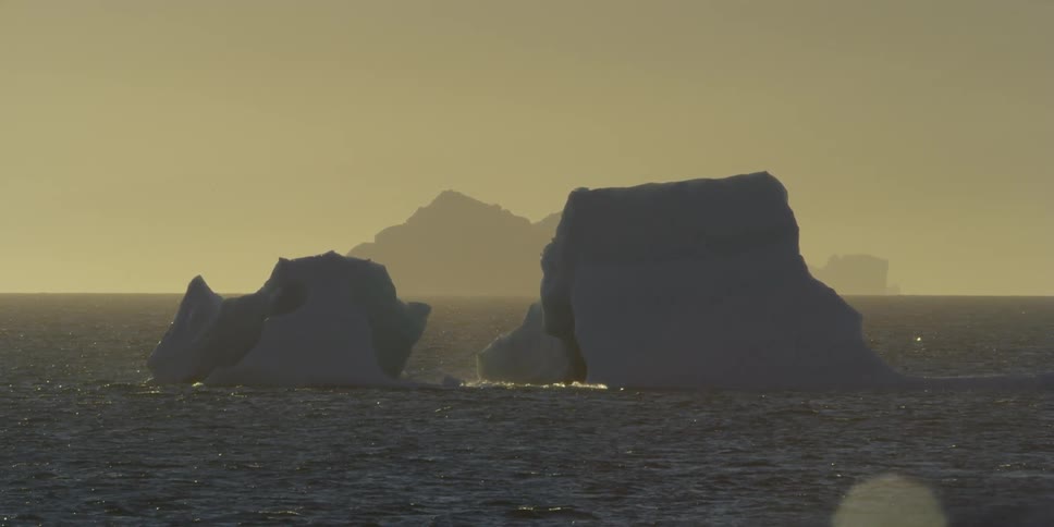 Two large rocks protruding from water on a hazy day