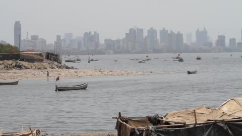 Boats float on a large body of water in front of a city