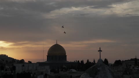 Cathedral dome and a cross against a cloudy sky