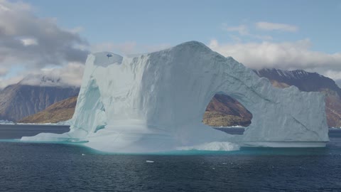 Large piece of ice with arches sticking out of water