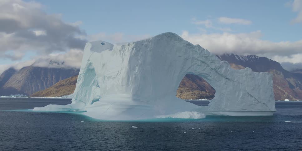 Large piece of ice with arches sticking out of water