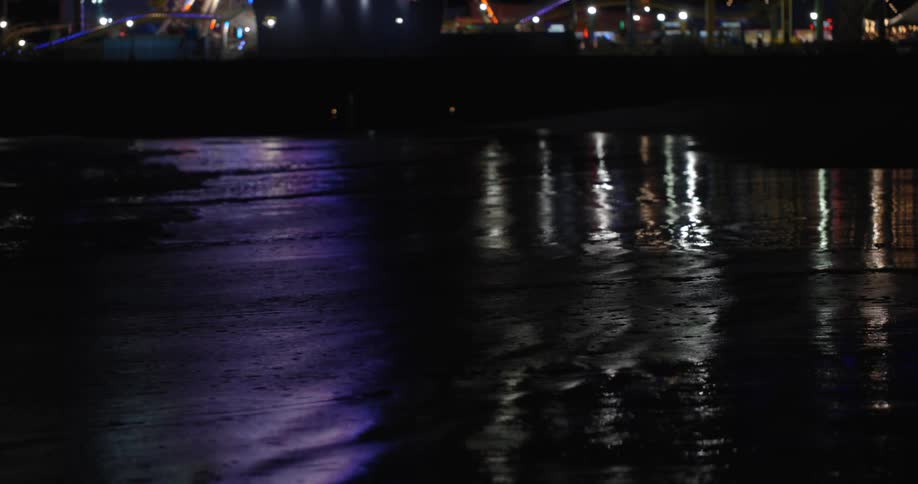 Water moves with the current as lights flash in the distance