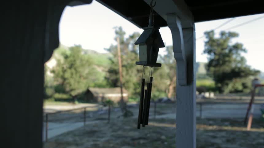A birdhouse with bells is seen rocking back and forth.]