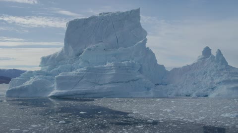 A large glacier sitting on a nearly ice covered sea during the day