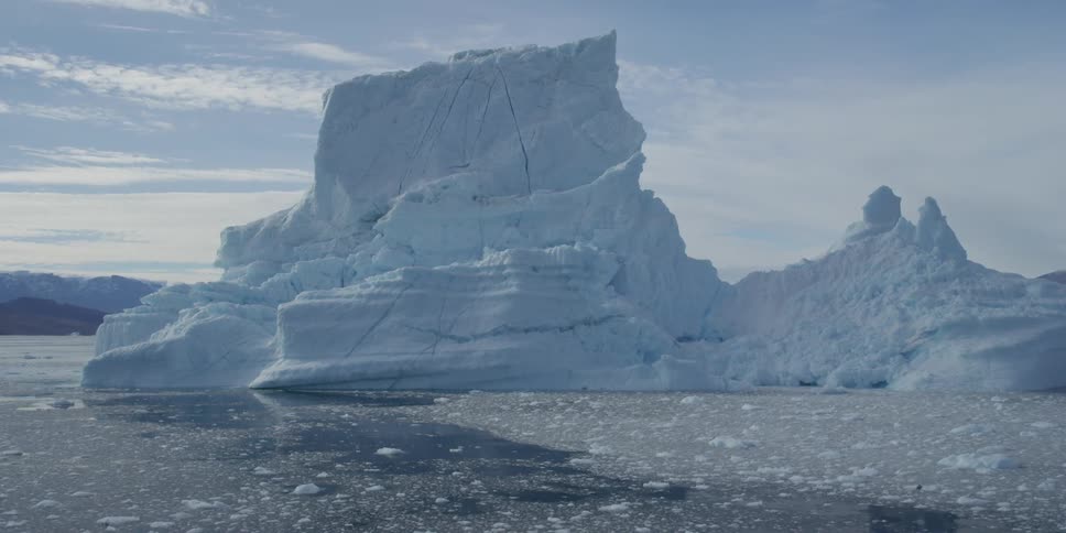 A large glacier sitting on a nearly ice covered sea during the day
