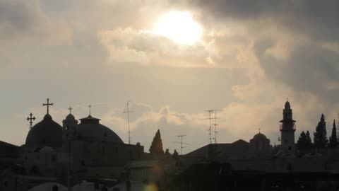 Sun shining through clouds over religious buildings