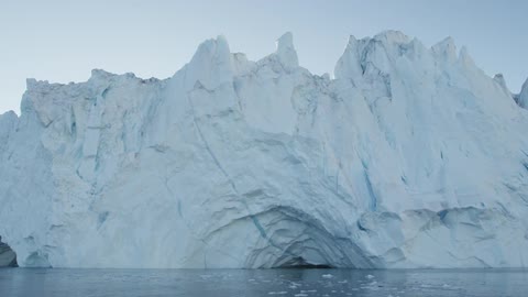 Large ice cliff with slow moving water in front during the day