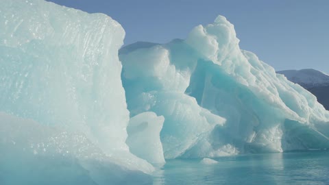 Blue glaciers sit with brilliant blue water at their base