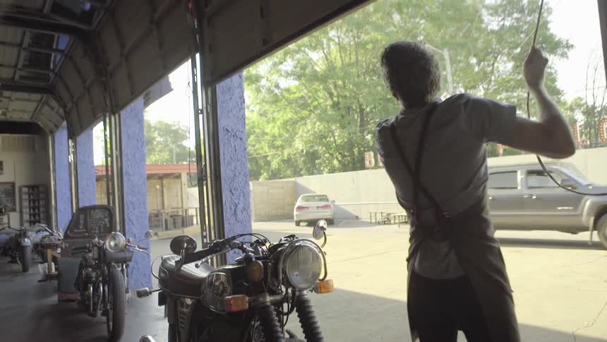 A man opens up garage door to coffee shop