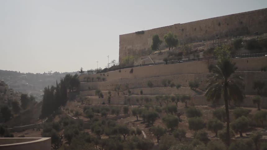 Cars driving next to a wall on a hill