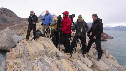 Group of men with cameras on tripods seaside