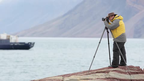 A man takes a photo near the water