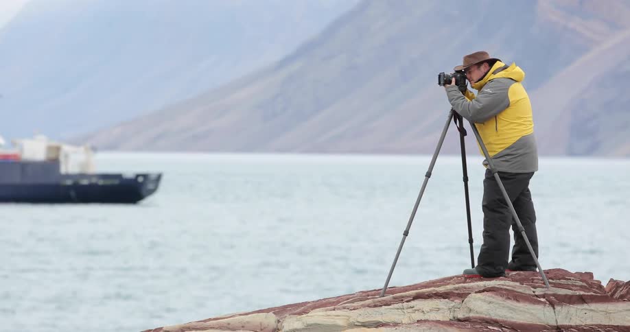 A man takes a photo near the water