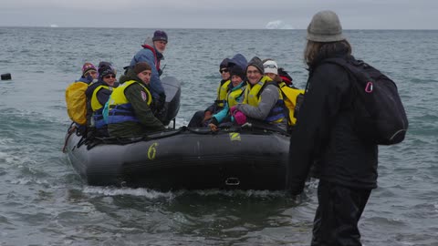 A group of people ride in a raft on the ocean