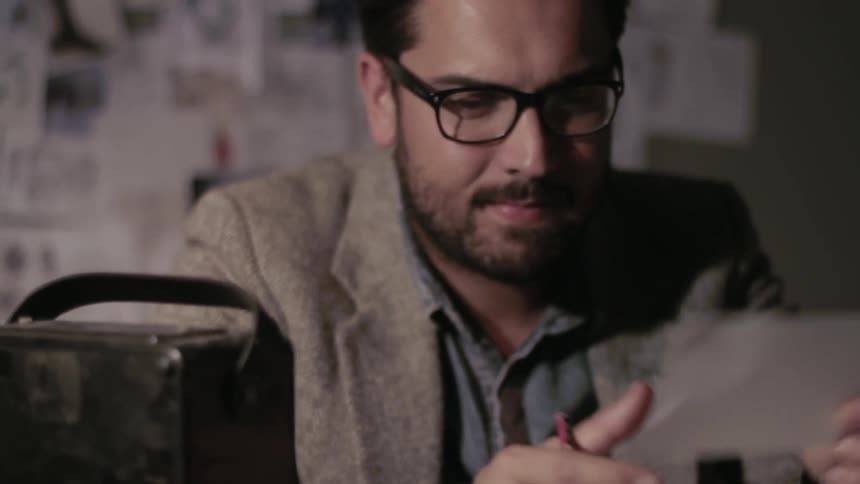 A seated man writes on a piece of paper