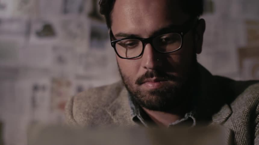 A man wearing glasses looks at a paper
