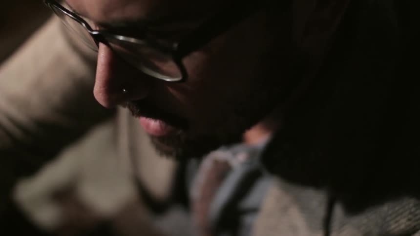 A man wearing glasses sits and concentrates