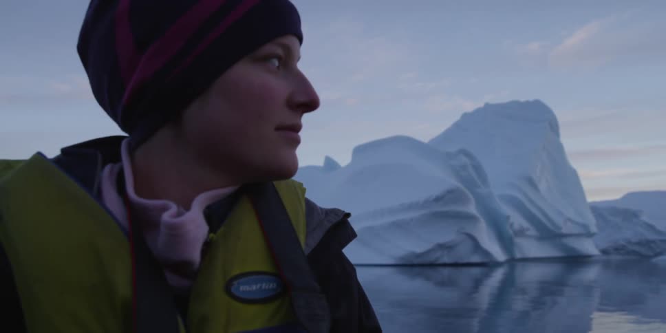 A woman sits near a glacier