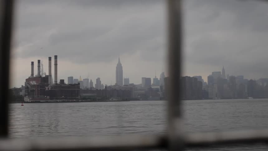 A city across the bay is seen through a window pane
