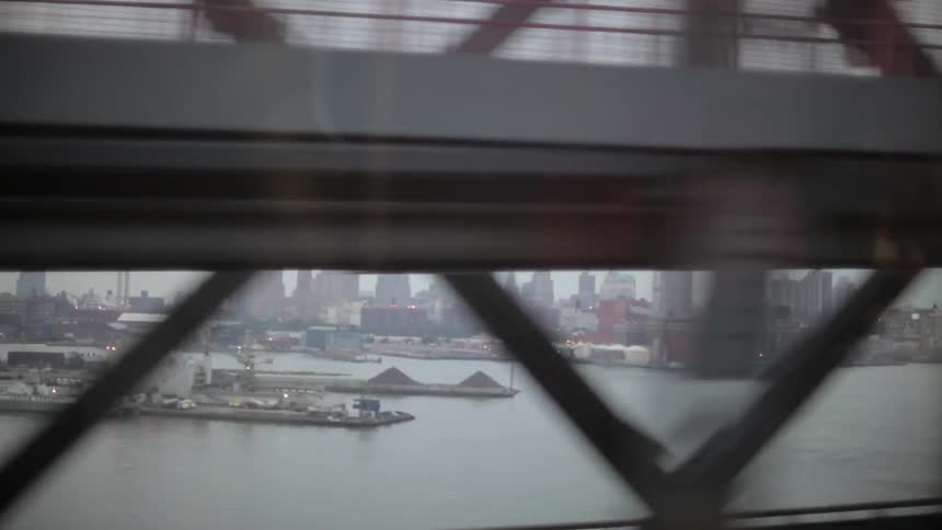A vehicle crosses a bridge that overlooks a city