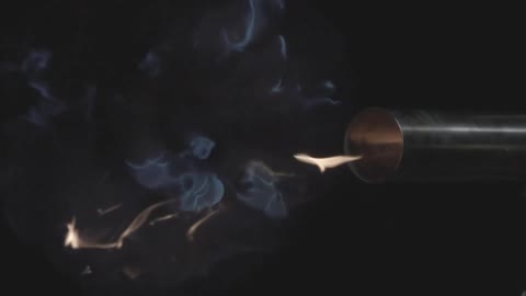 A flame shoots out of a metal barrel and smoke evaporates