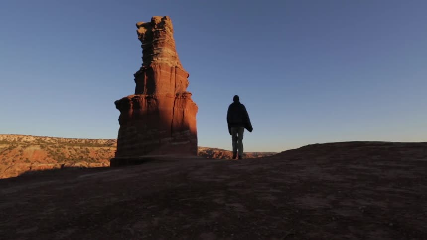 A person walks near a rock formation