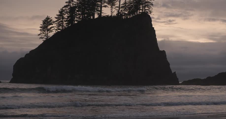 A land formation protrudes from the ocean and is covered with trees