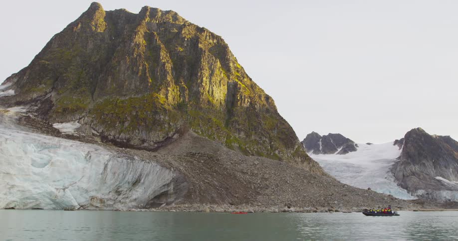 A boat floats in front of a mountain