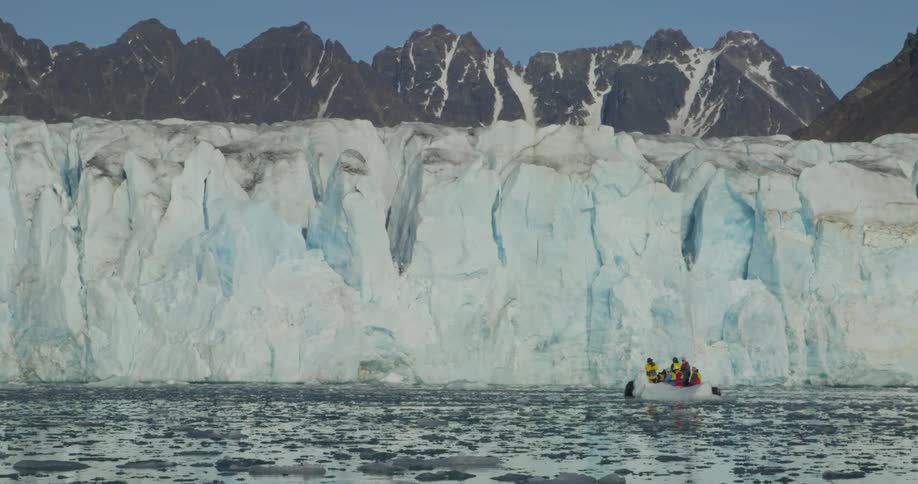 A boat full of people float near a glacier