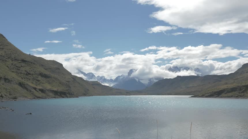 Clouds float over the mountains and a glistening lake