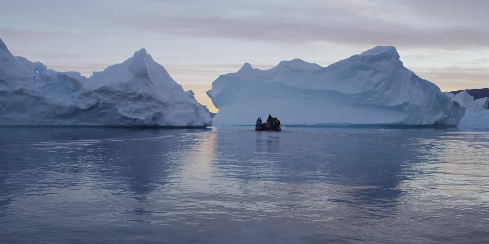 A group of people drift past an iceberg