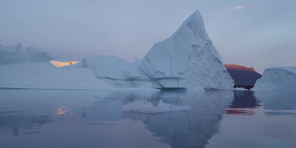 A tiny piece of ice floating in front of an iceberg
