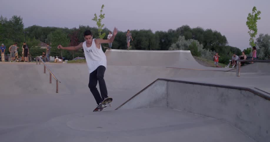 A skateboarder descends into a skatepark and performs a trick