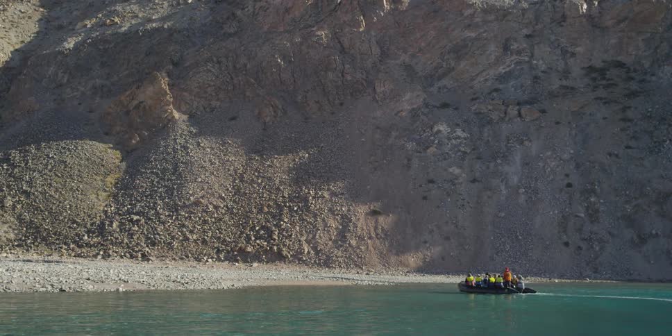 Many people on a boat in front of mountains