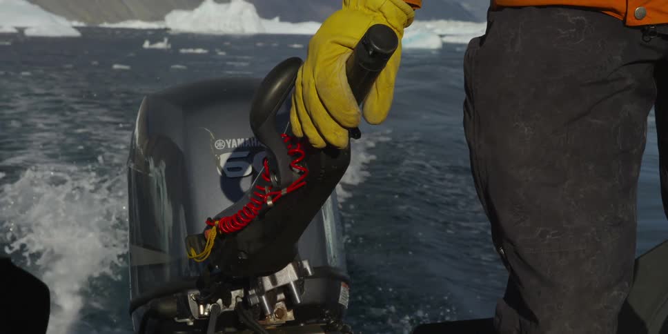 A person steers a boat from the motor