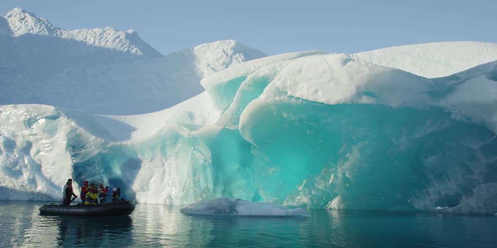 People row in a raft past the ice berg