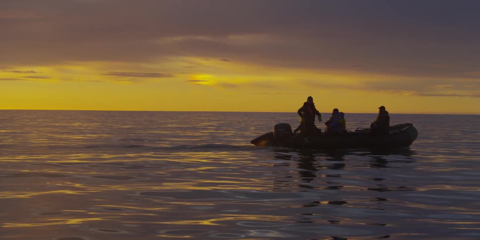 People on raft on the ocean at sunset