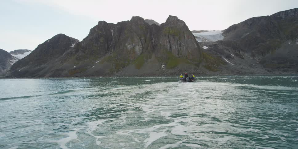 A group of people on a boat approach a mountain