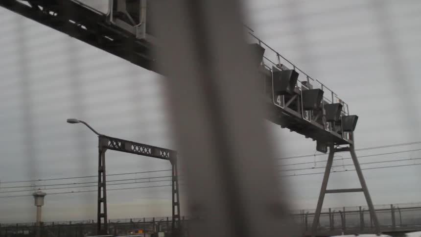 A bus passes under signals on a bridge