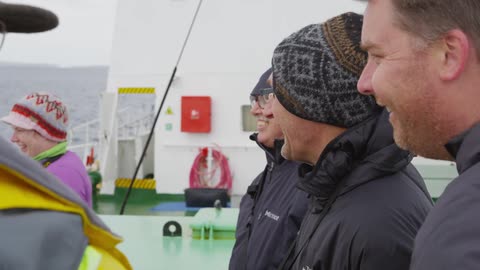 People in coats and a boat laugh together