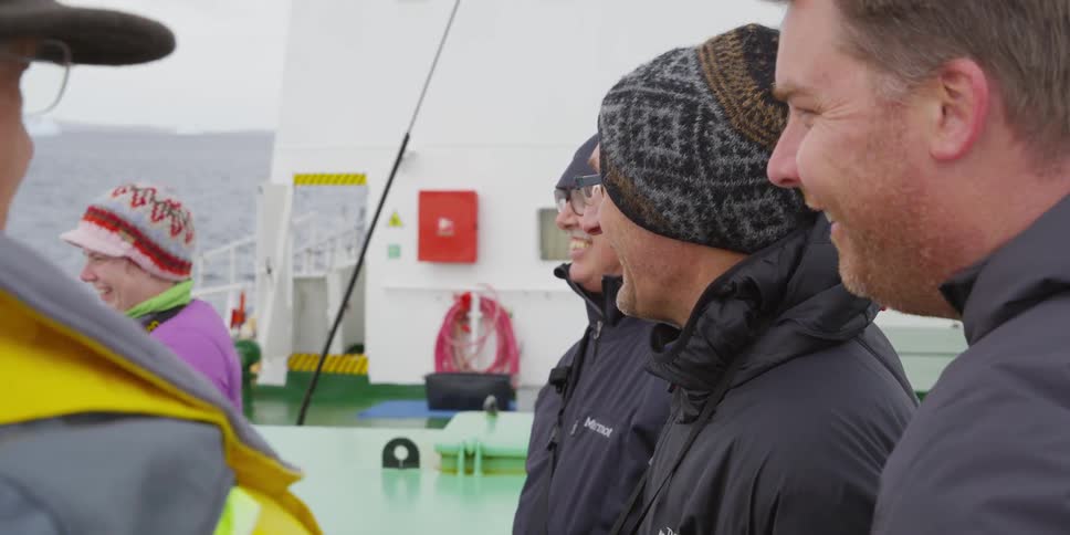 People in coats and a boat laugh together