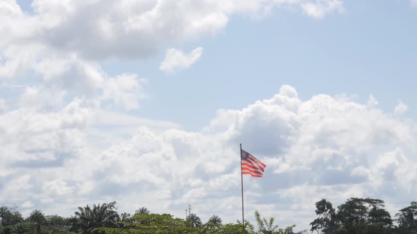 An american flag billows against a cloudy sky