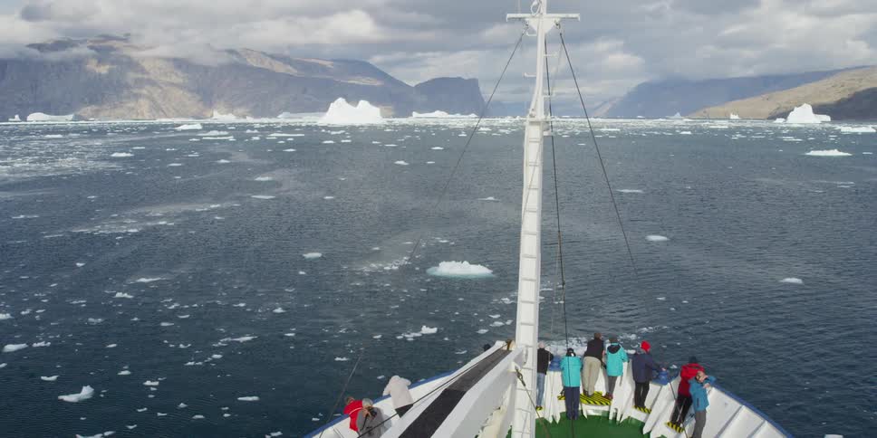 A group of people on a boat sail in the arctic ocean