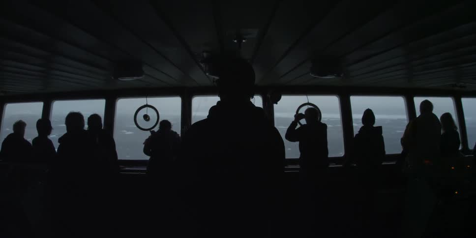 People look out of the windows of a large boat with binoculars