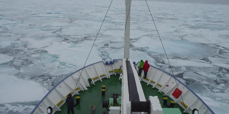 People on a boat that is slowly moving through icy water