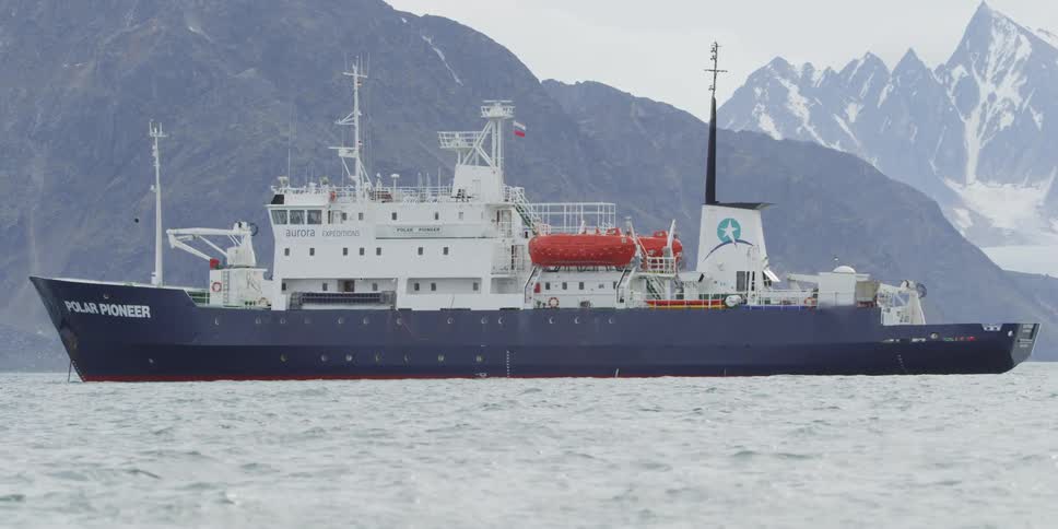 A ship floats in front of mountains