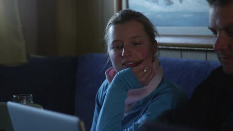 A woman is sitting next to a man while they both look at the screen of a laptop computer