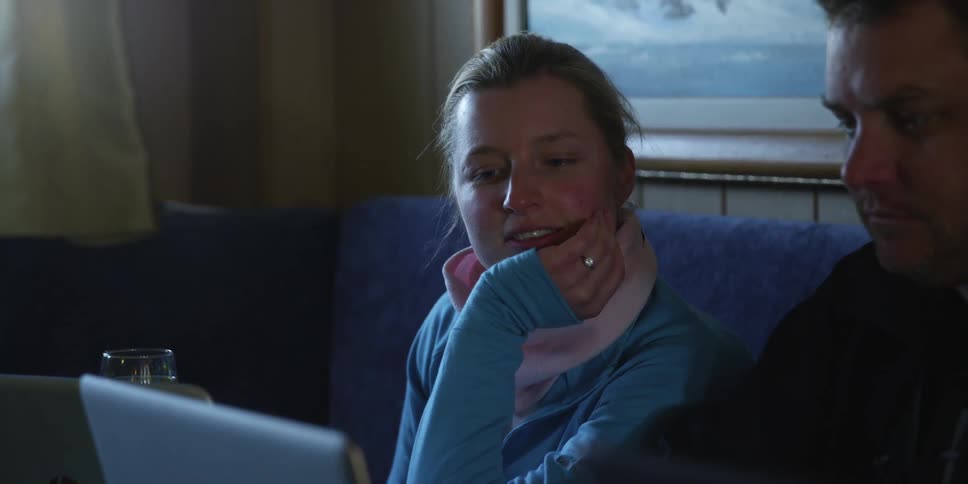 A woman is sitting next to a man while they both look at the screen of a laptop computer